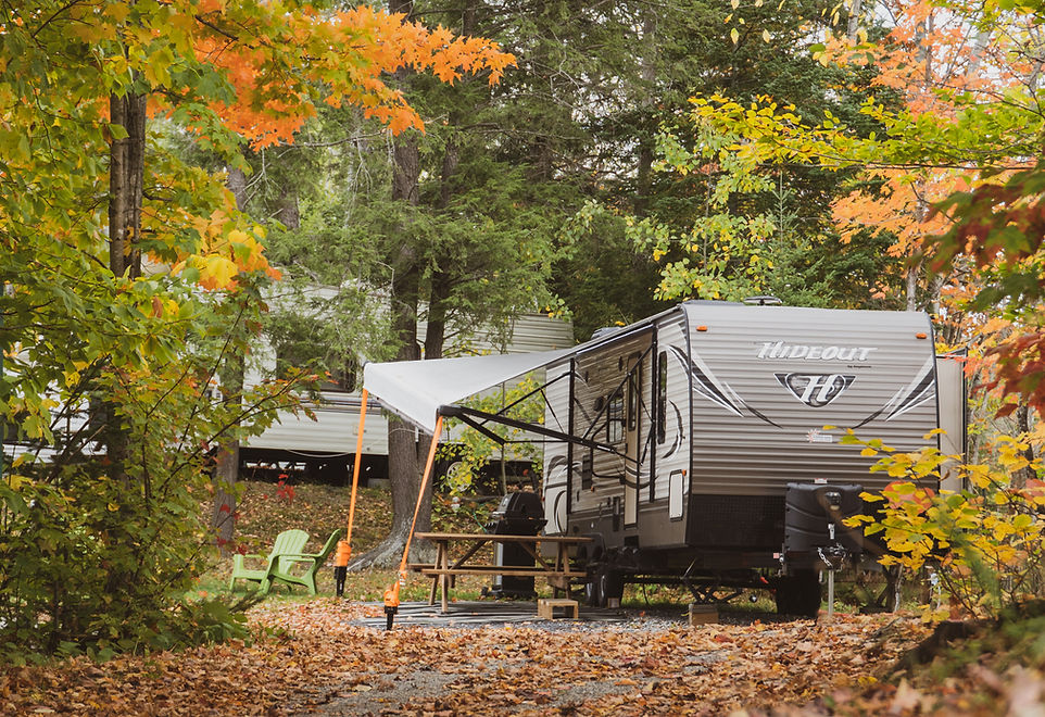 Vue d'une roulotte installé sur un emplacement du Camping Lac Magog pendant les couleurs de l'automne.